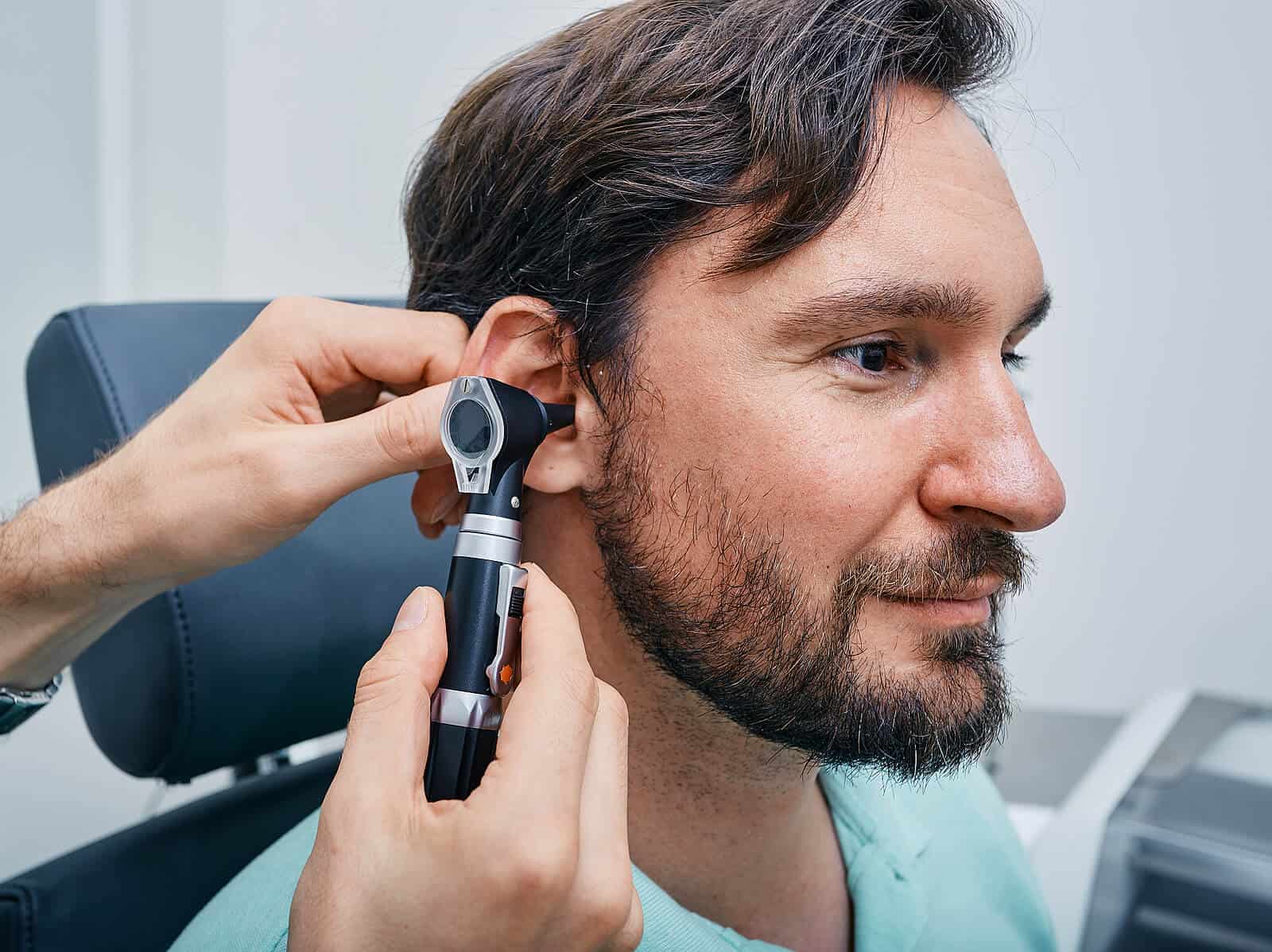 audiologist examining ear of male patient