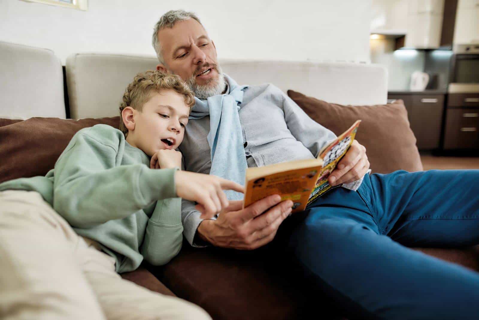 grandfather reading book to grandchild while the grandchild points at page