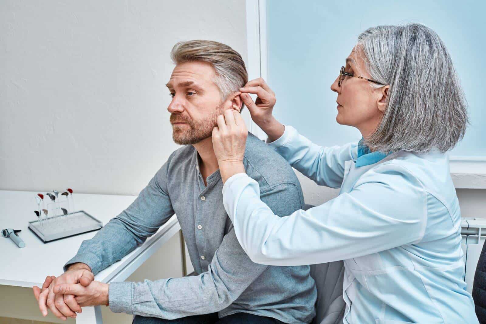 audiologist fitting hearing aid onto patient