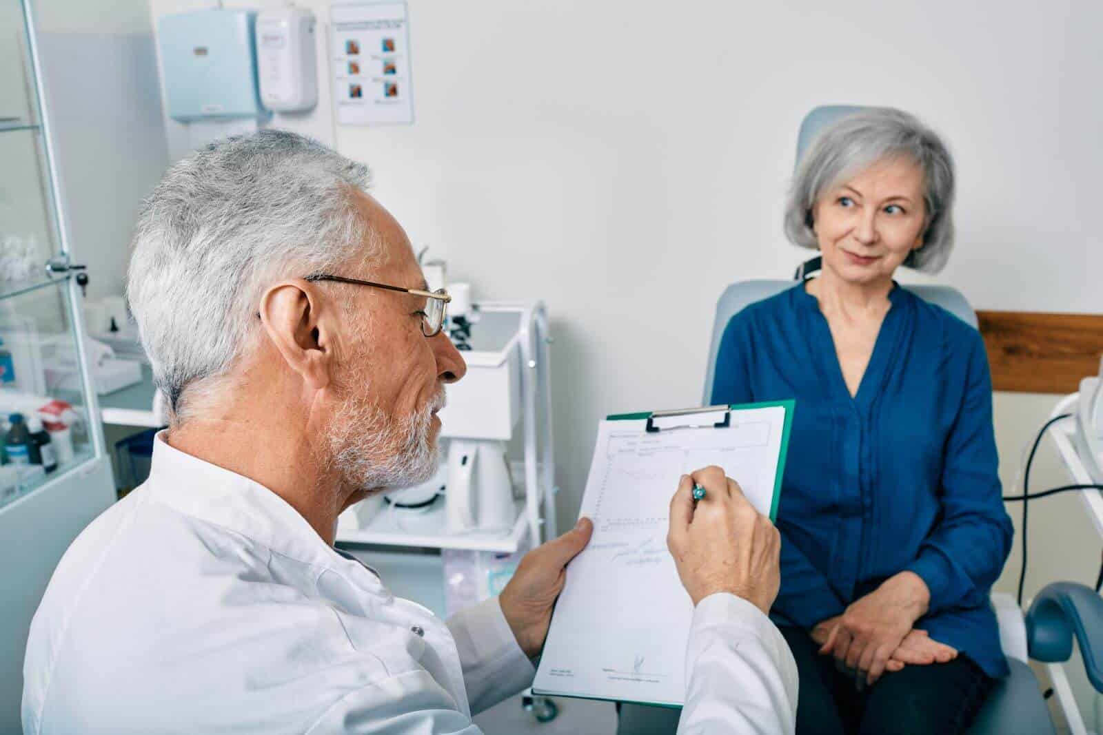 older audiologist going over test results or other form with older patient