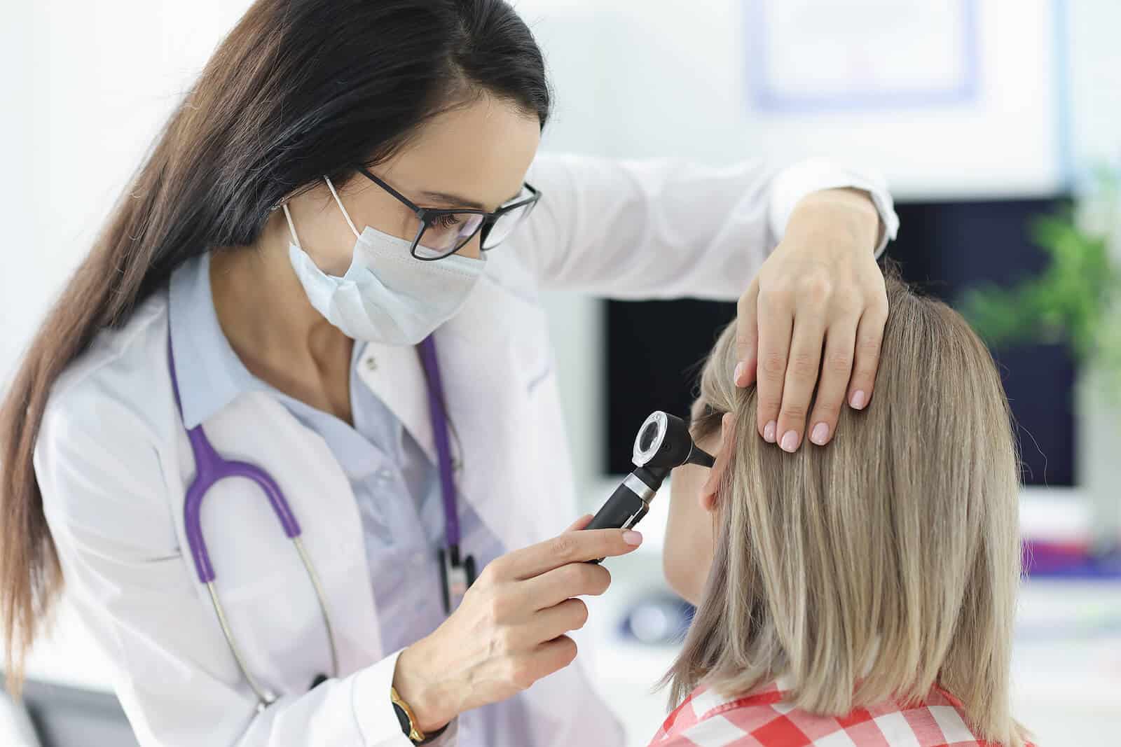 audiologist examining ear with tool